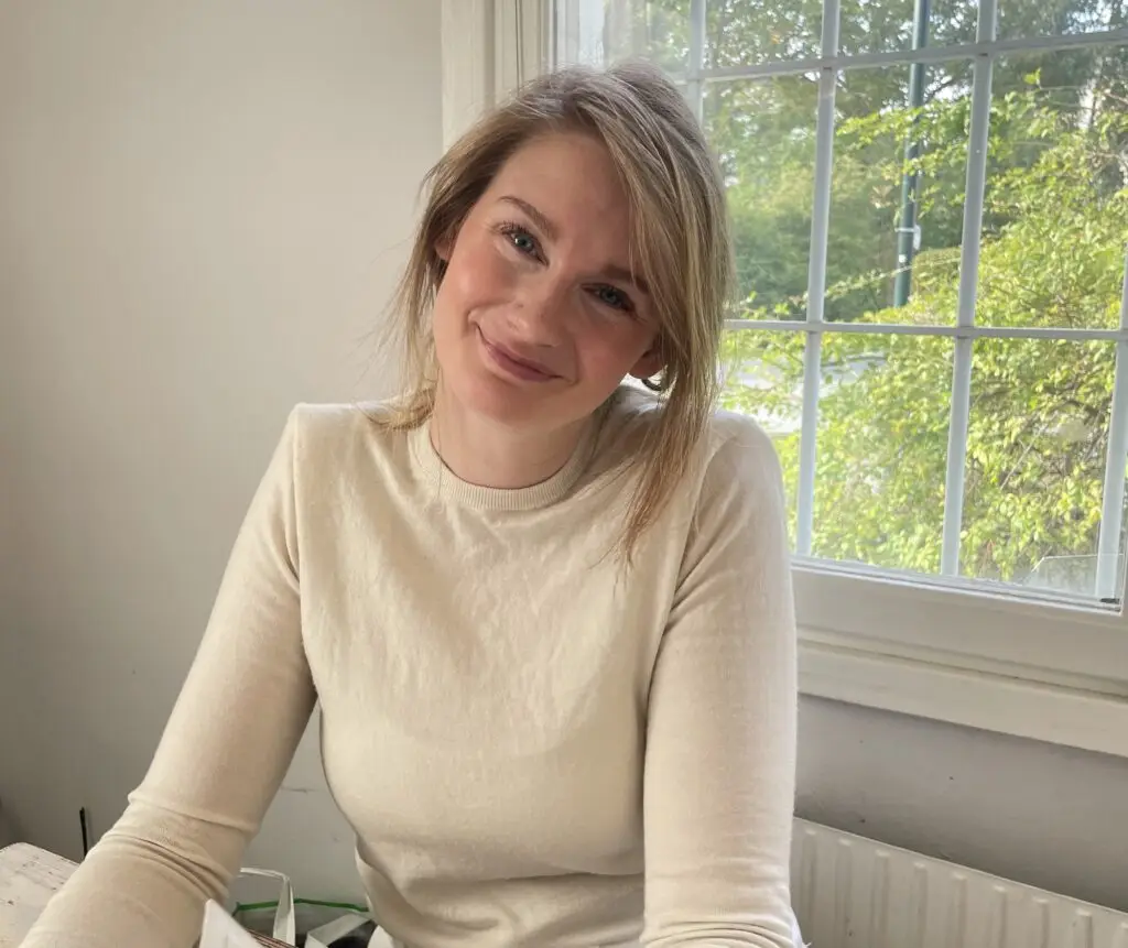 Josefine Berg ler vid fönstret i ljus tröja